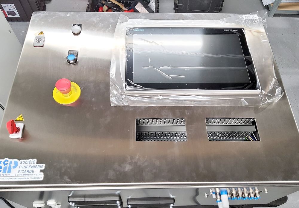 Coffret déporté en inox : écran tactile sous film de protection, arrêt d'urgence, réarmement, sectionneur et connectique pneumatique.