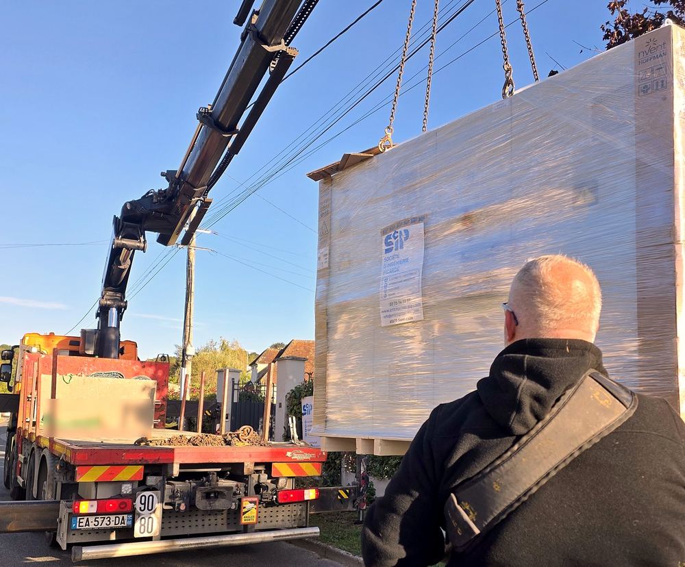 Chargement de l'armoire emballée sur un camion-grue devant l'atelier SIP.